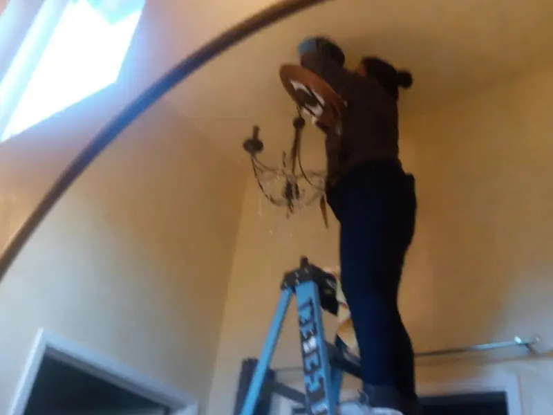 Electrician installing a chandelier in a Bloomer residence